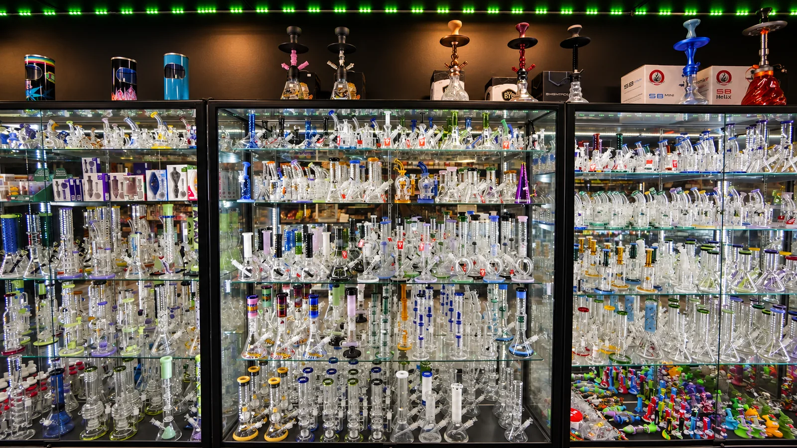 A wall of glass pieces, with hookahs on top of the cases